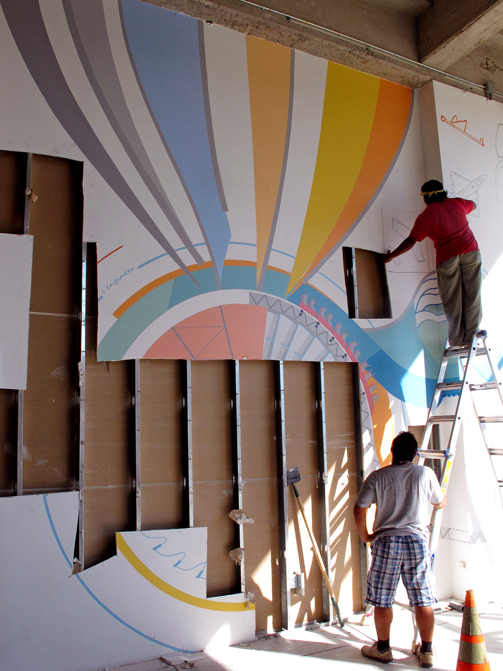 Two men on a ladder cutting out parts of the mural. The large abstract balloon portion is intact, but most of the rest is gone, exposing the metal studs inside the wall.
