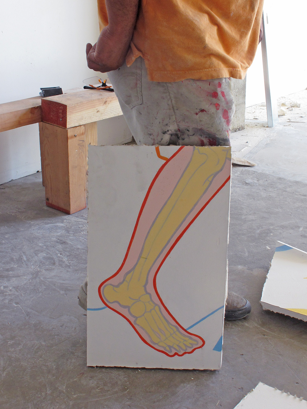 Part of the leg cut out in front of the leg of a man working to cut the mural apart.