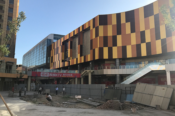 construction photo of cinema and sky plaza from exterior internal street, mixed-use architecture project in Tangshan, China