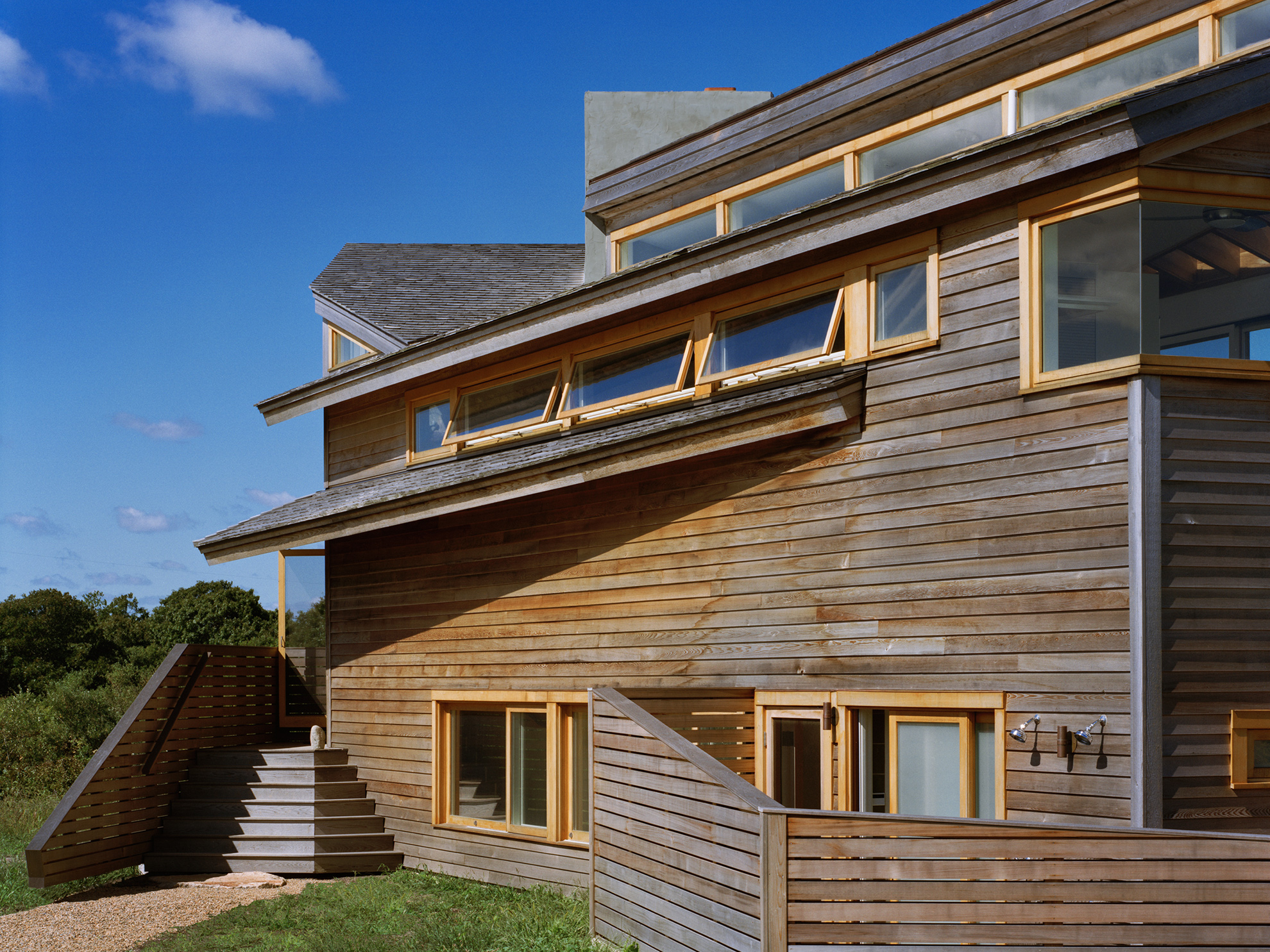 In the front, the angled cedar roofs and angled cedar exterior walls project past the massing of the house.