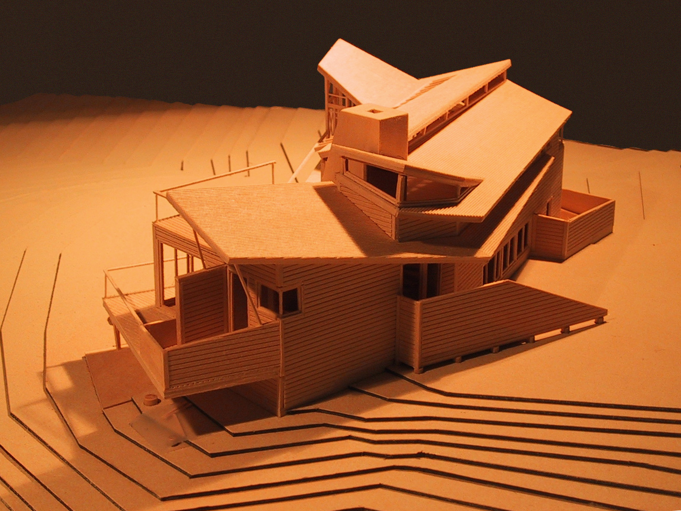 Wood model of house shows layered angled roofs, and organic way the deck and exterior walls extend into the landscape beyond the body of the house.