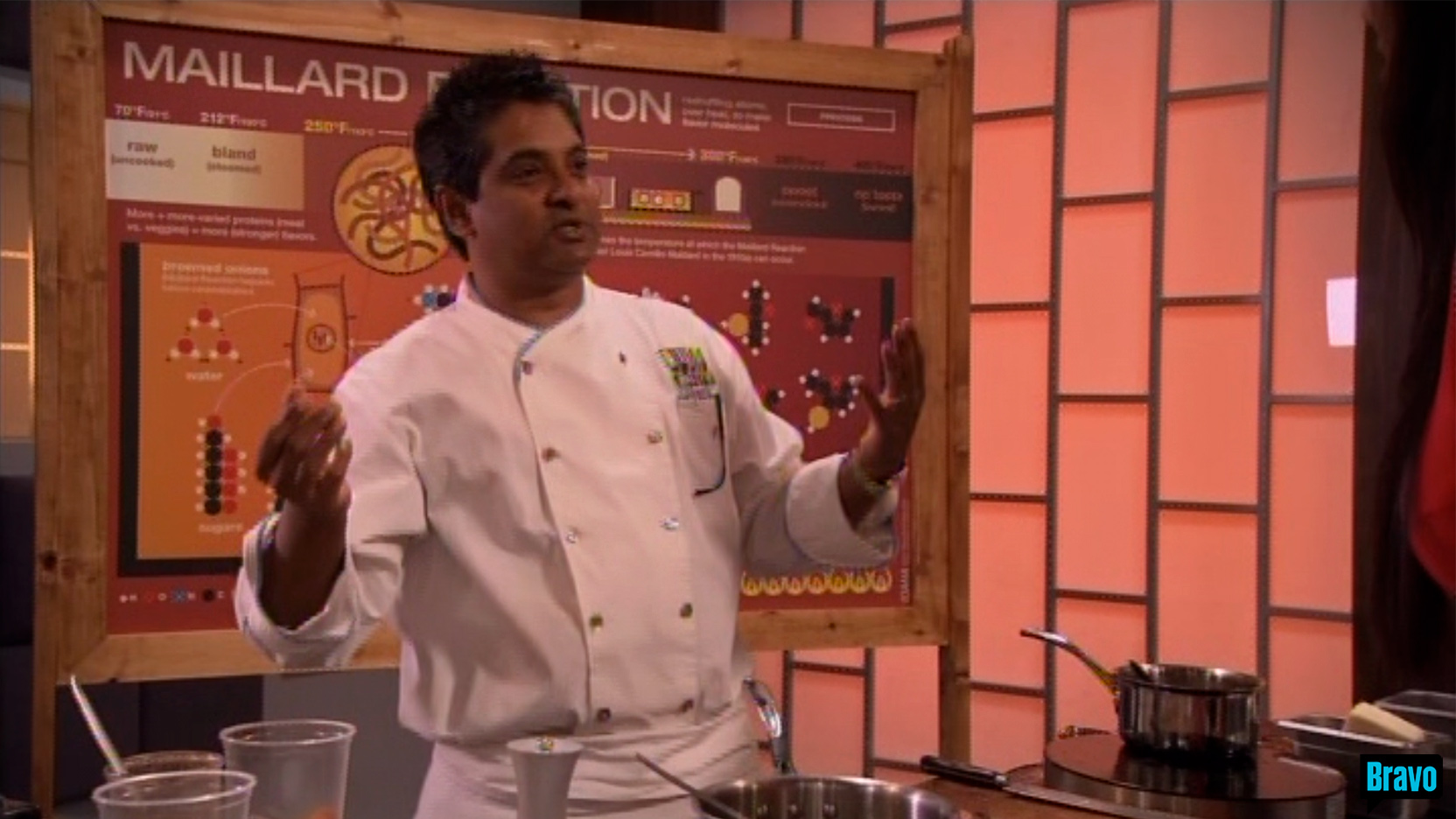 Chef Floyd Cardoz, dressed in a white chef outfit, explains something with his arms up and open,
                                                                            behind a table with cooking equipment and 
                                                                            in front of a large MAILLARD REACTION illustration framed in stained pine, on the set of
                                                                            Bravo TV&rsquo;s Top Chef Masters &ldquo;Blinded Me with Science&rdquo; episode.