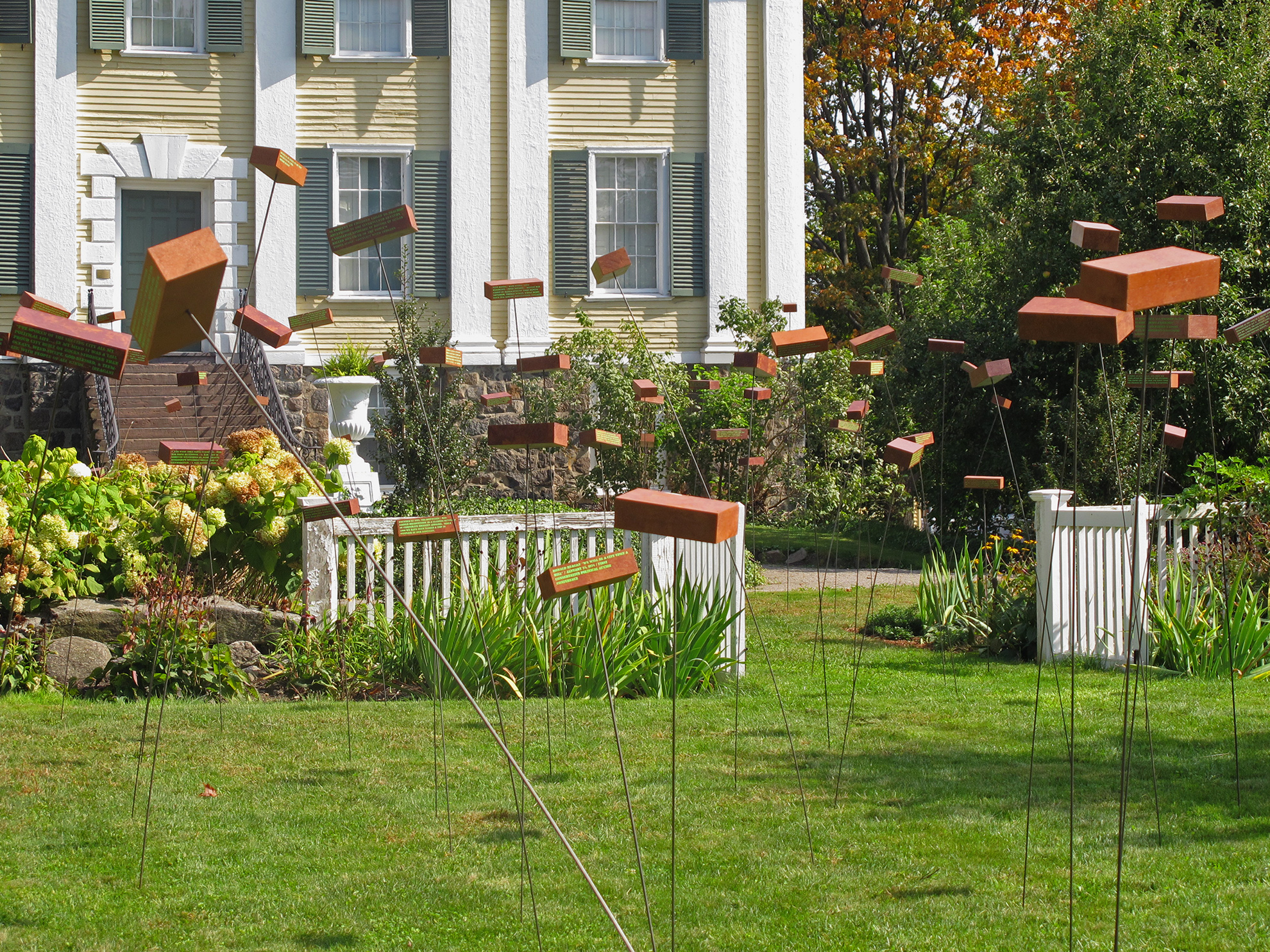 field of floating fake bricks seen against backdrop of historic Shirley Eustis House house and garden