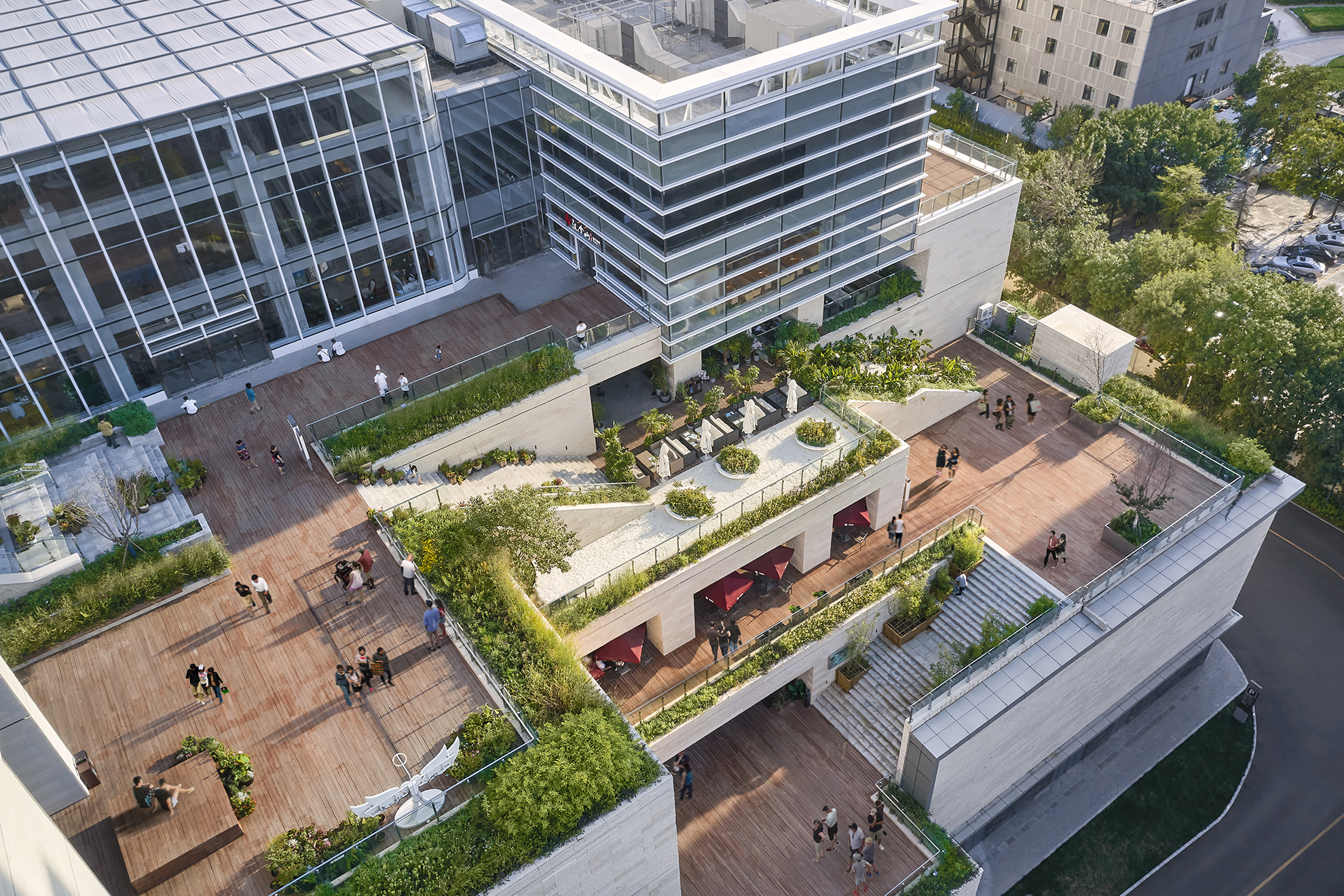 Aerial view of the North zone terraced landscape plazas showing how they cascade down and connect to each other. 
                                                            The walls and stairs and clad in stone, and often bordered by planters. 
                                                            The terraces have wood floors.