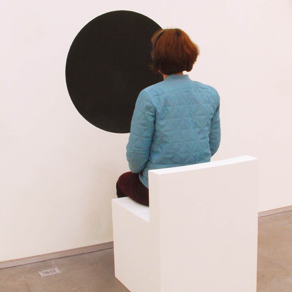 a woman (Ioana) faces a large black circle painted on a wall and while listening to audio art