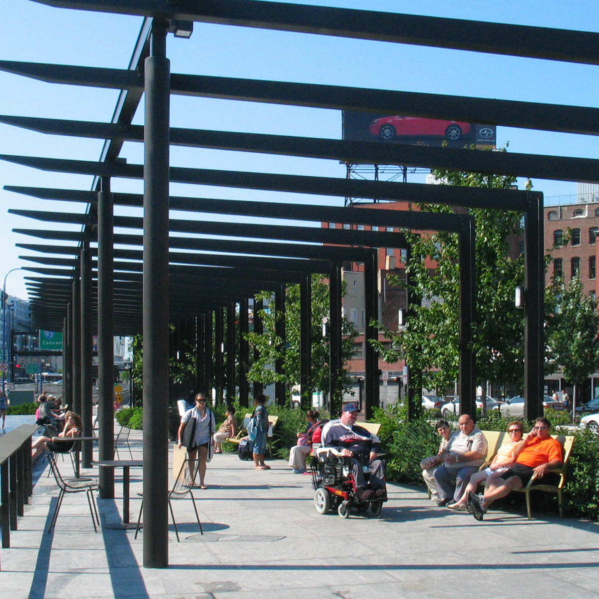 people seated on benches under the North End Parks pergolas, one riding a wheelchair
