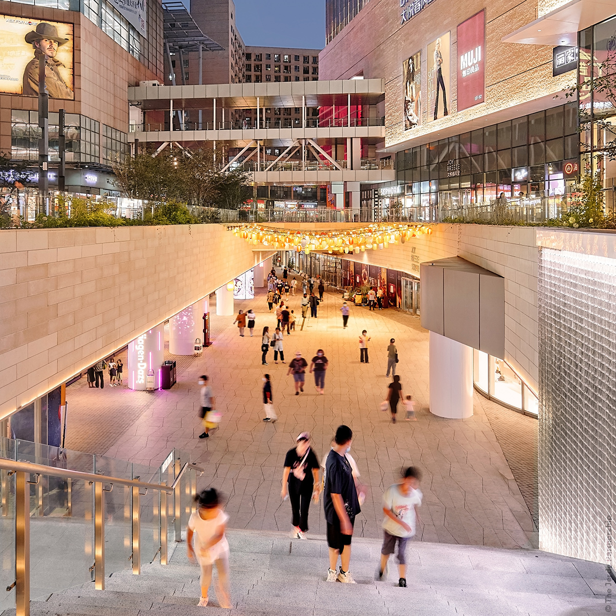 people in a multilevel outdoor shopping center in China which goes underground in an outdoor nicely lit space