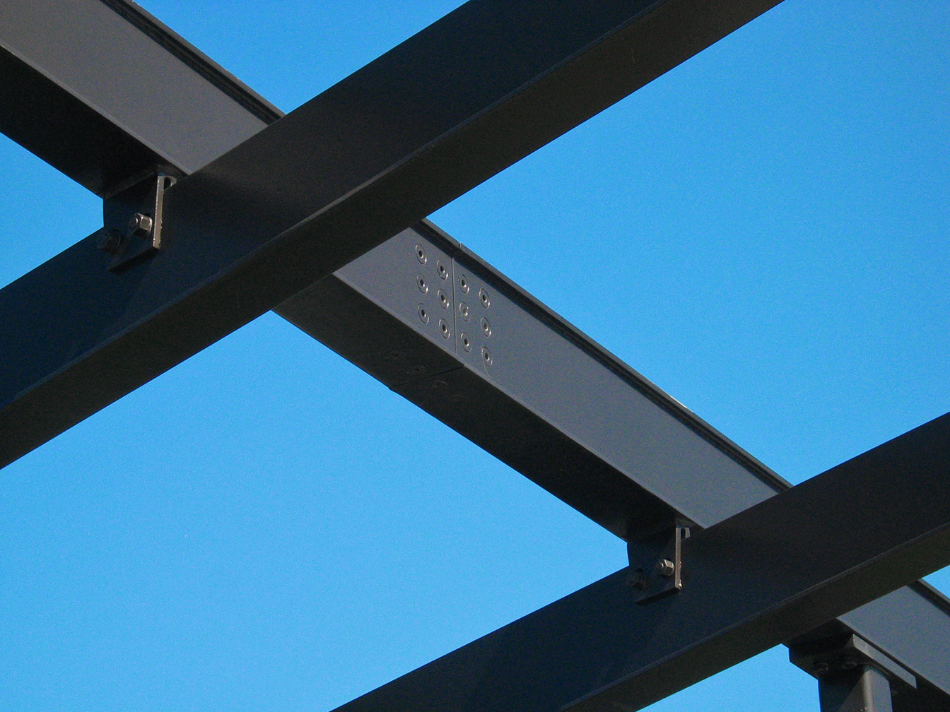 Close-up view of a beam, showing the recessed-screw connection between beam sections, and the way that the purlins are hung off of the beam.