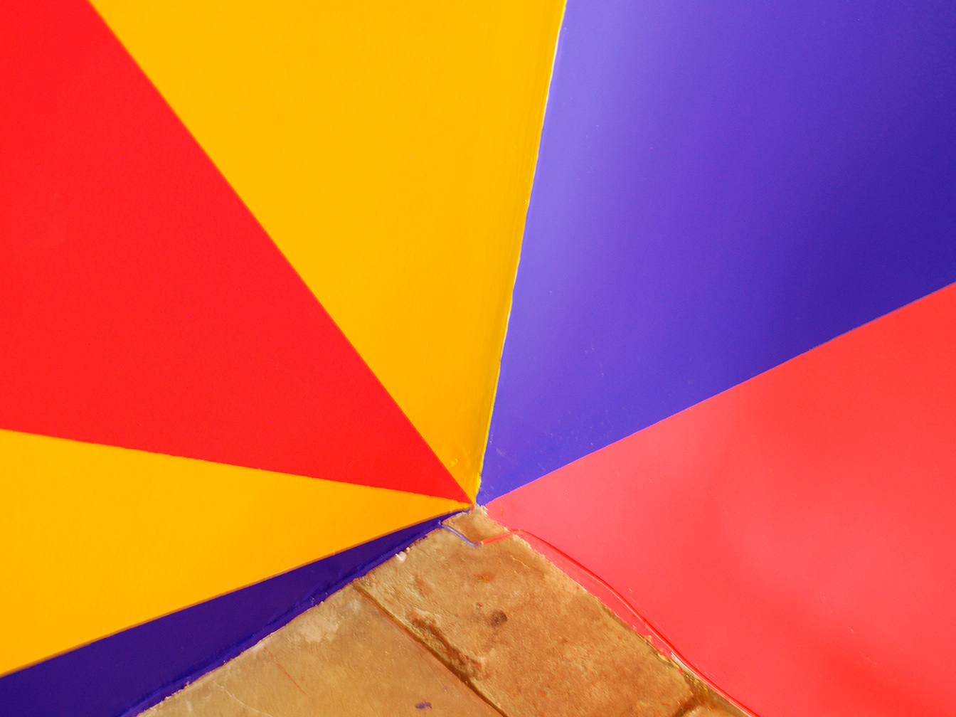 Zoom in on bottom back corner showing triangular areas of blue, yellow, and red paint coming to a point.