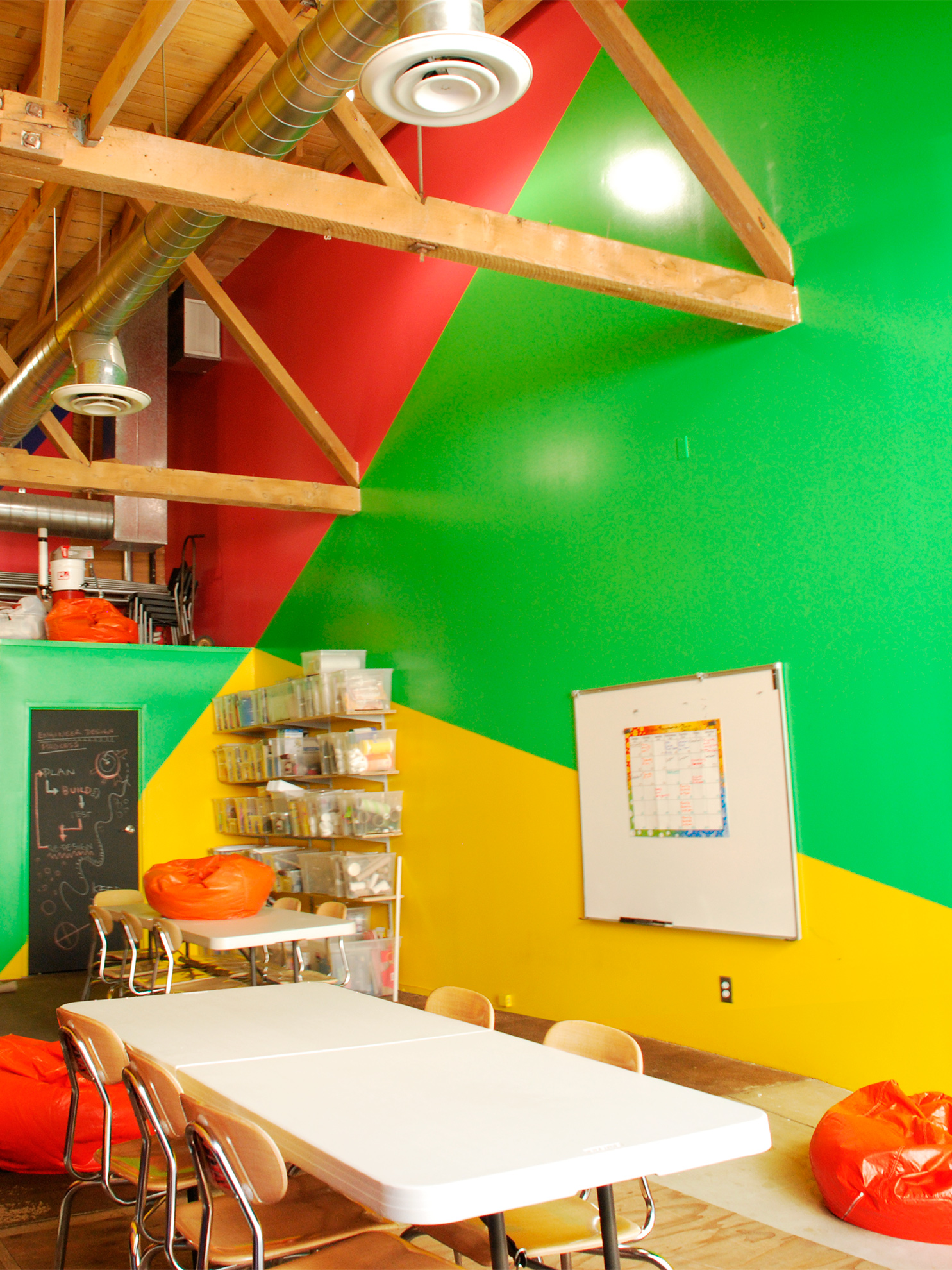 Wall of bathroom pop-out volumen cut diagonally in half in green vs yellow paint, with its door painted in chalkboard paint, 
                                                                        The wall to the right of it reversing direction of green and yellow paint, enlarging the perspective toward the front.
                                                                        The part of the wall beyond the highest green paint area, and up behind the bathroom wall, is painted red.